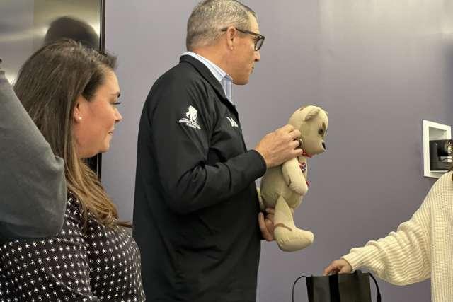 Gen. 迈克尔·林宁顿手持荣誉熊. “修复行动”项目主管艾普莉·萨宾在他的右边. 